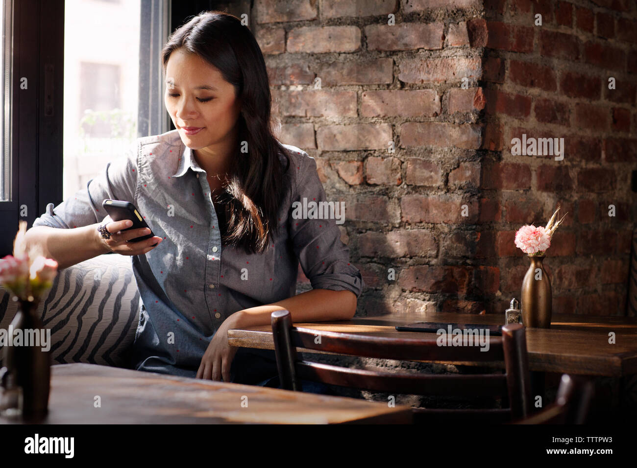 Donna che utilizza smart phone mentre è seduto in cafe Foto Stock