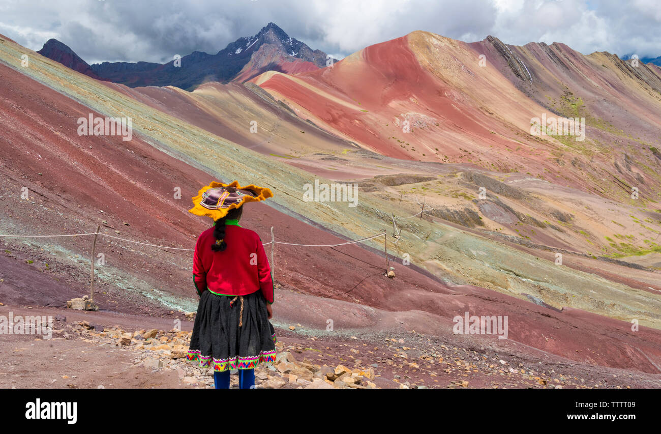 Il quechua donna con le colline dipinte di Rainbow Mountain (Vinicunca), Provincia di Cusco, Perù Foto Stock