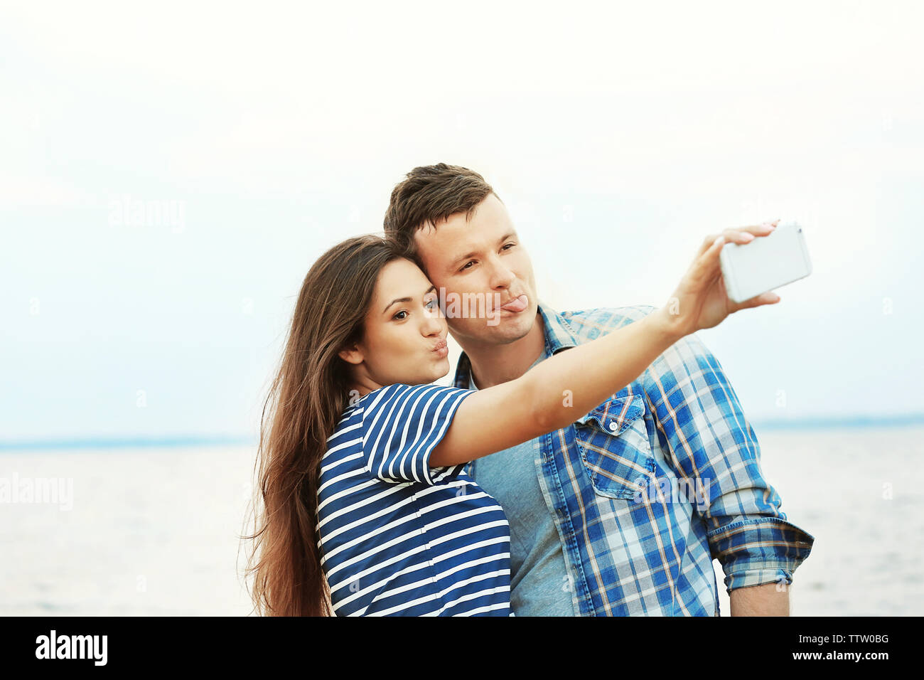 Bella coppia Giovane tenendo selfie sulla riva del fiume Foto Stock