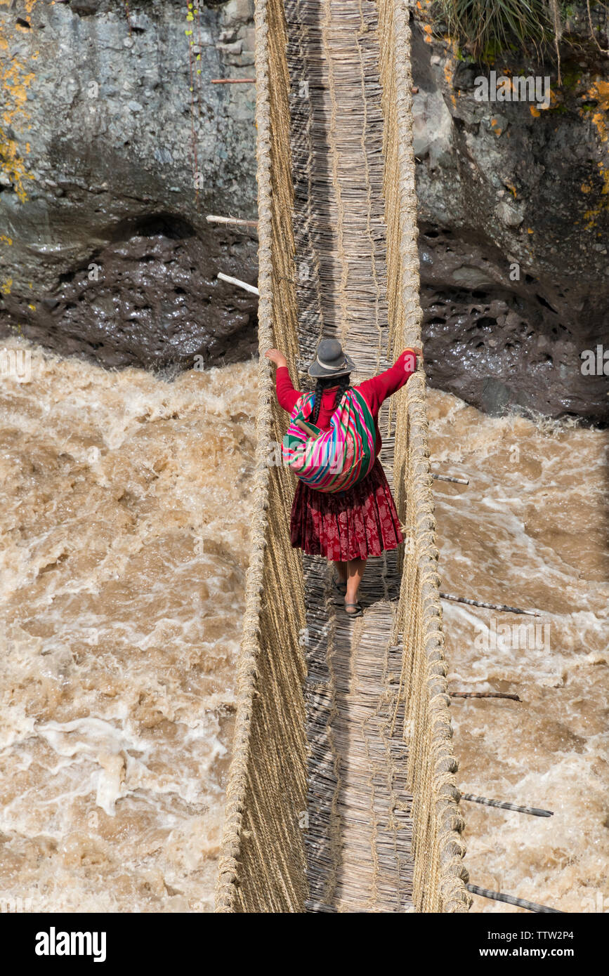 Il quechua donna attraversando Queshuachaca (Q'eswachaka durante) ponte di corde, uno degli ultimi Inca permanente intrecciato ponti, Quehue, provincia di Canas, Perù Foto Stock
