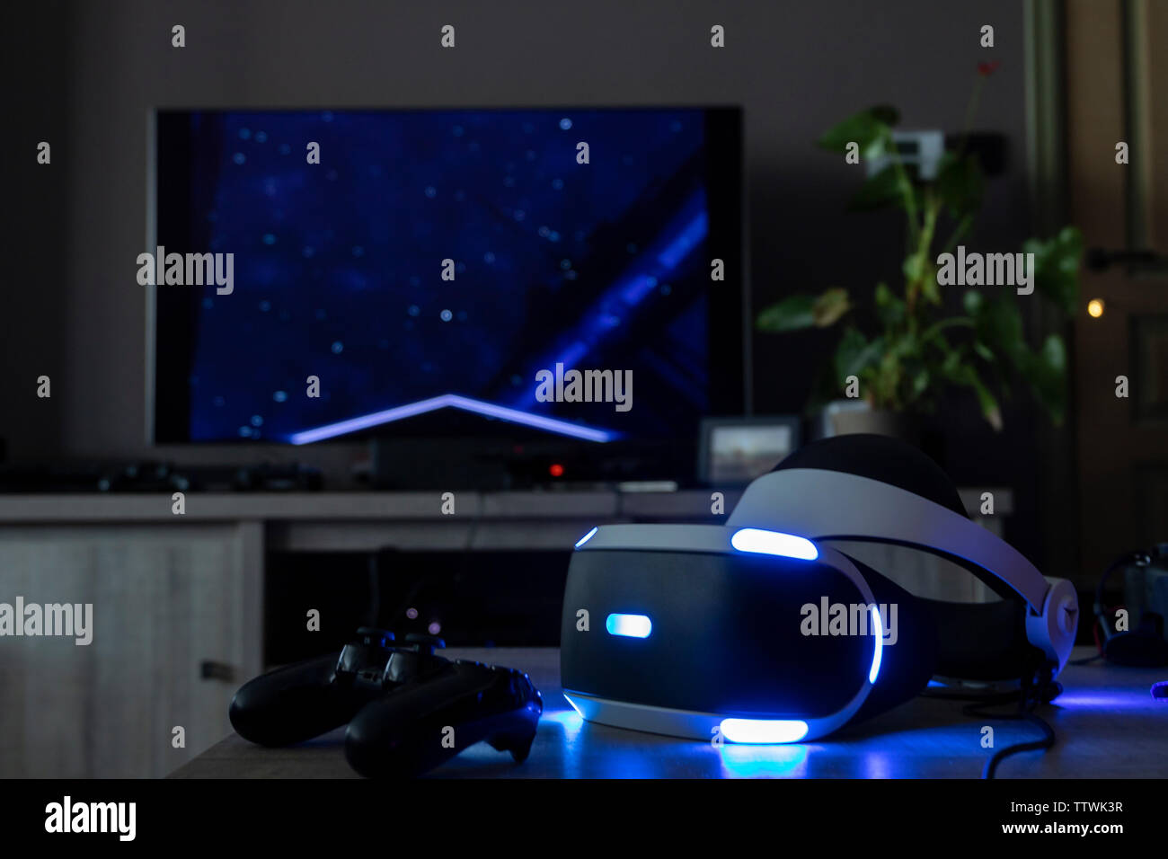 BRECHT, Belgio - 12 giugno 2019: una Playstation auricolare VR illumina il tavolo accanto a un controller di Playstation in una buia stanza vivente. Foto Stock