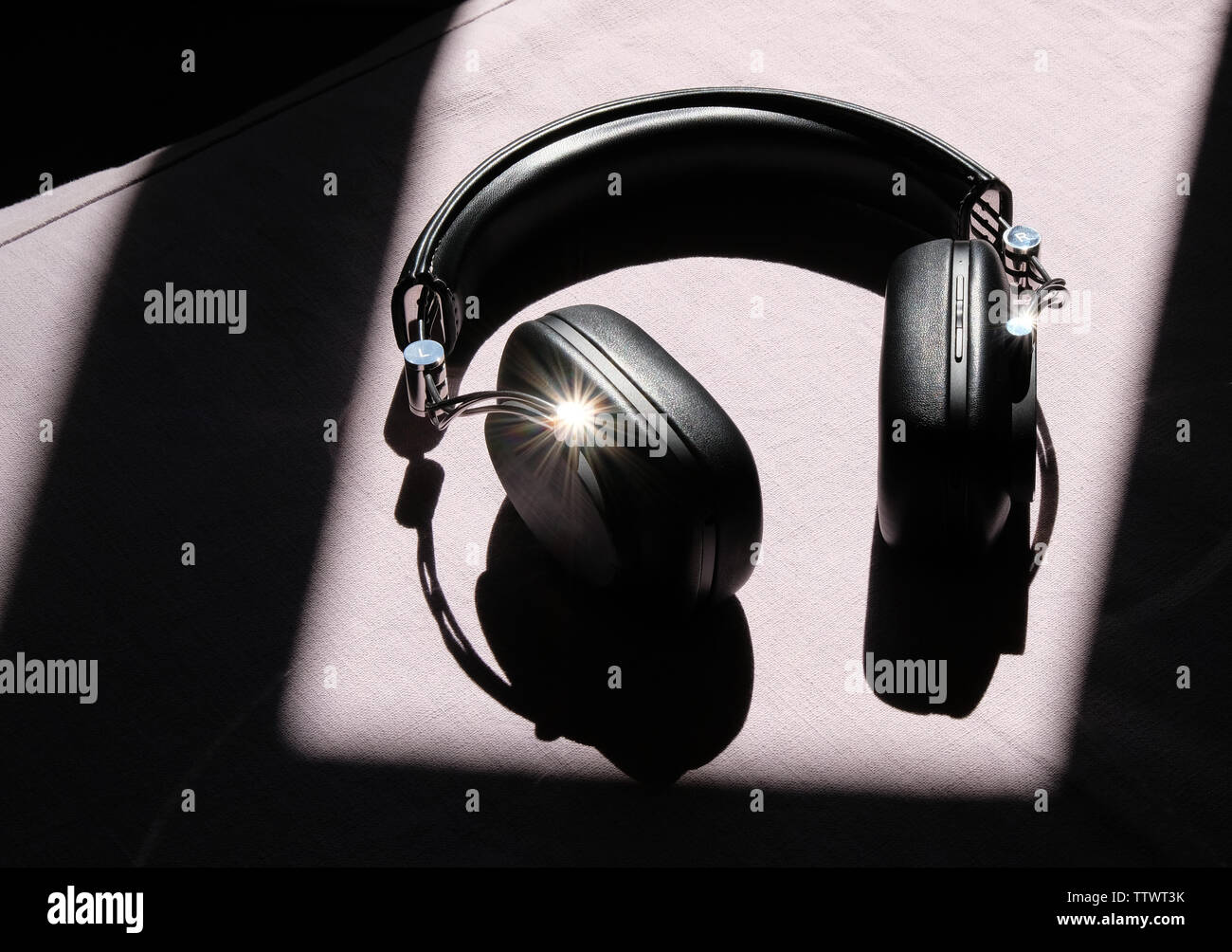 Nero cuffie wireless sdraiati al sole su un tavolo bianco Foto Stock