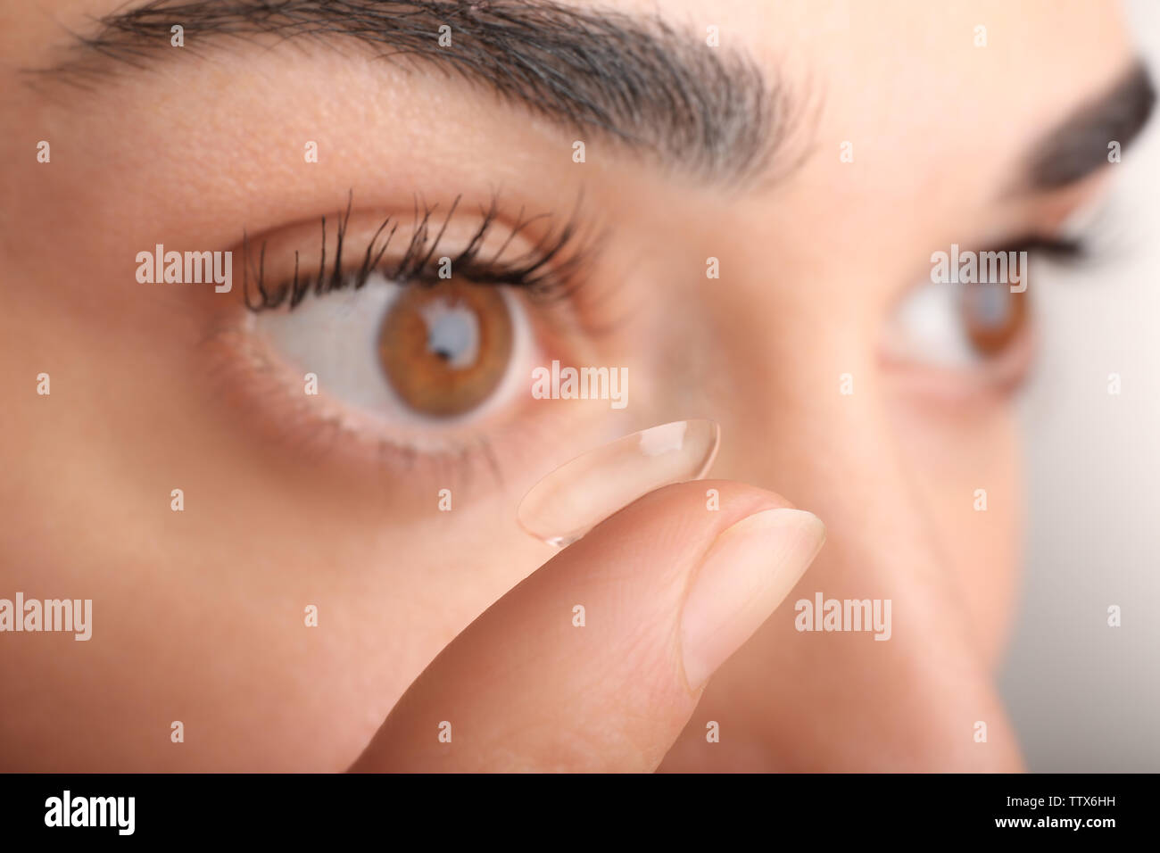 Giovane donna mettendo la lente a contatto nel suo occhio, vista ravvicinata. Medicina e vision concept Foto Stock