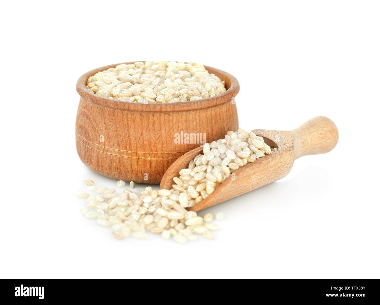 Brown a grana corta di riso nel recipiente di legno e scoop su sfondo bianco Foto Stock