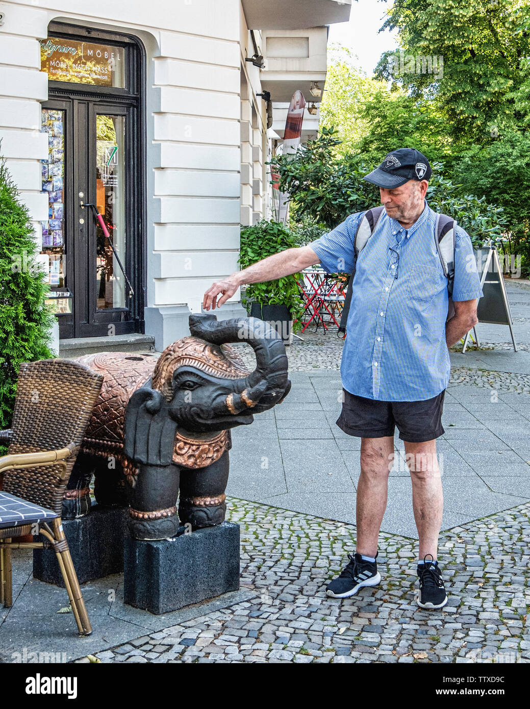 Senior maschio anziano turista ammira elefante decorativo esterno Avtaar ristorante indiano, una caffetteria e un cocktail bar su Stuttgarter Platz, Berlin Foto Stock