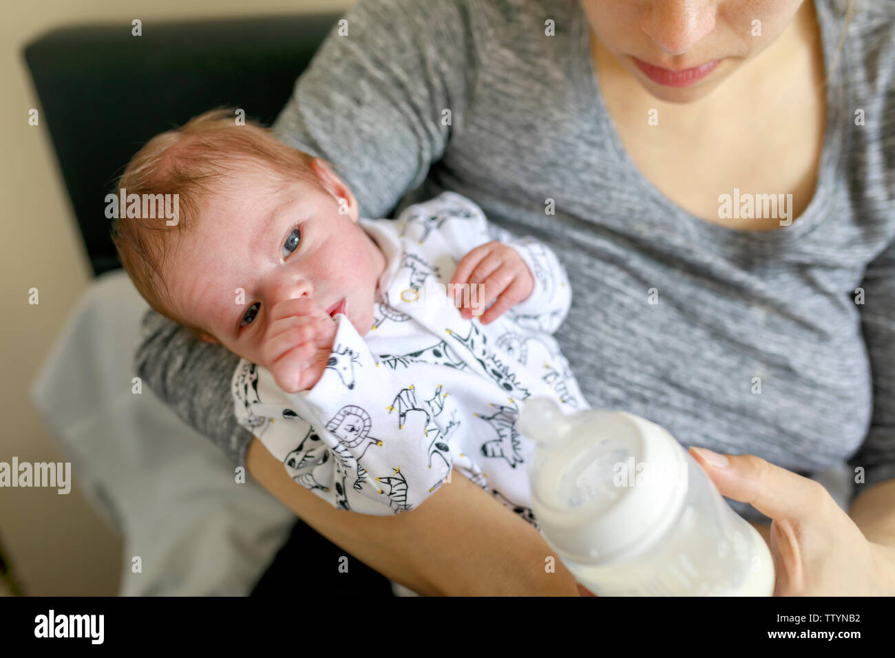 Felice giovane madre che allatta il suo piccolo neonato con un biberon a casa. Salute e benessere cura della madre. Donna che allatta il bambino Foto Stock