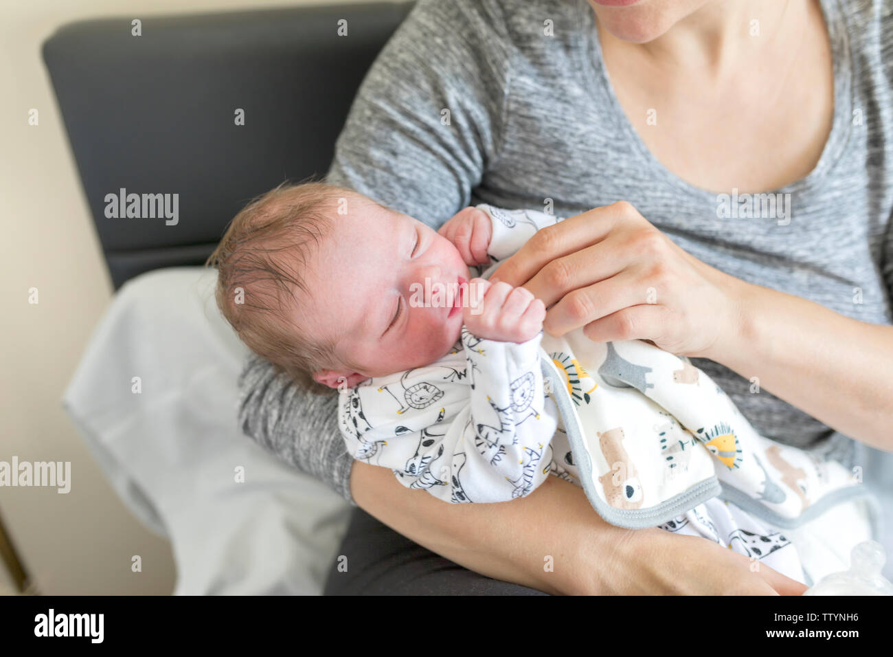 Madre giovane che allatta il latte ad un neonato. Una donna pulisce il viso del bambino e si nutre con una bottiglia di latte Foto Stock