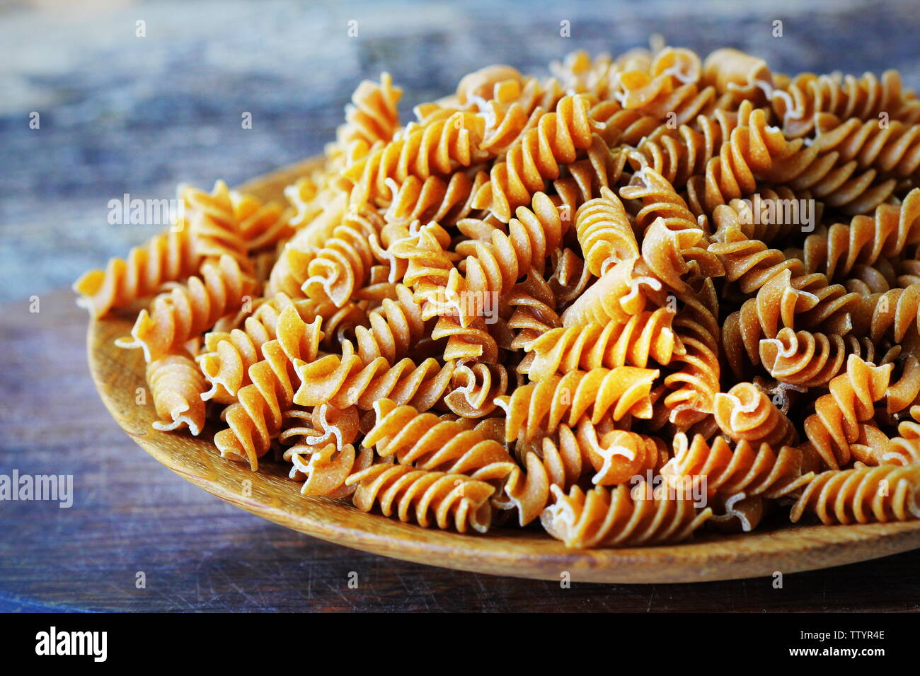 Fusilli integrali in un piatto. Pasta integrale su una tavola di legno Foto Stock