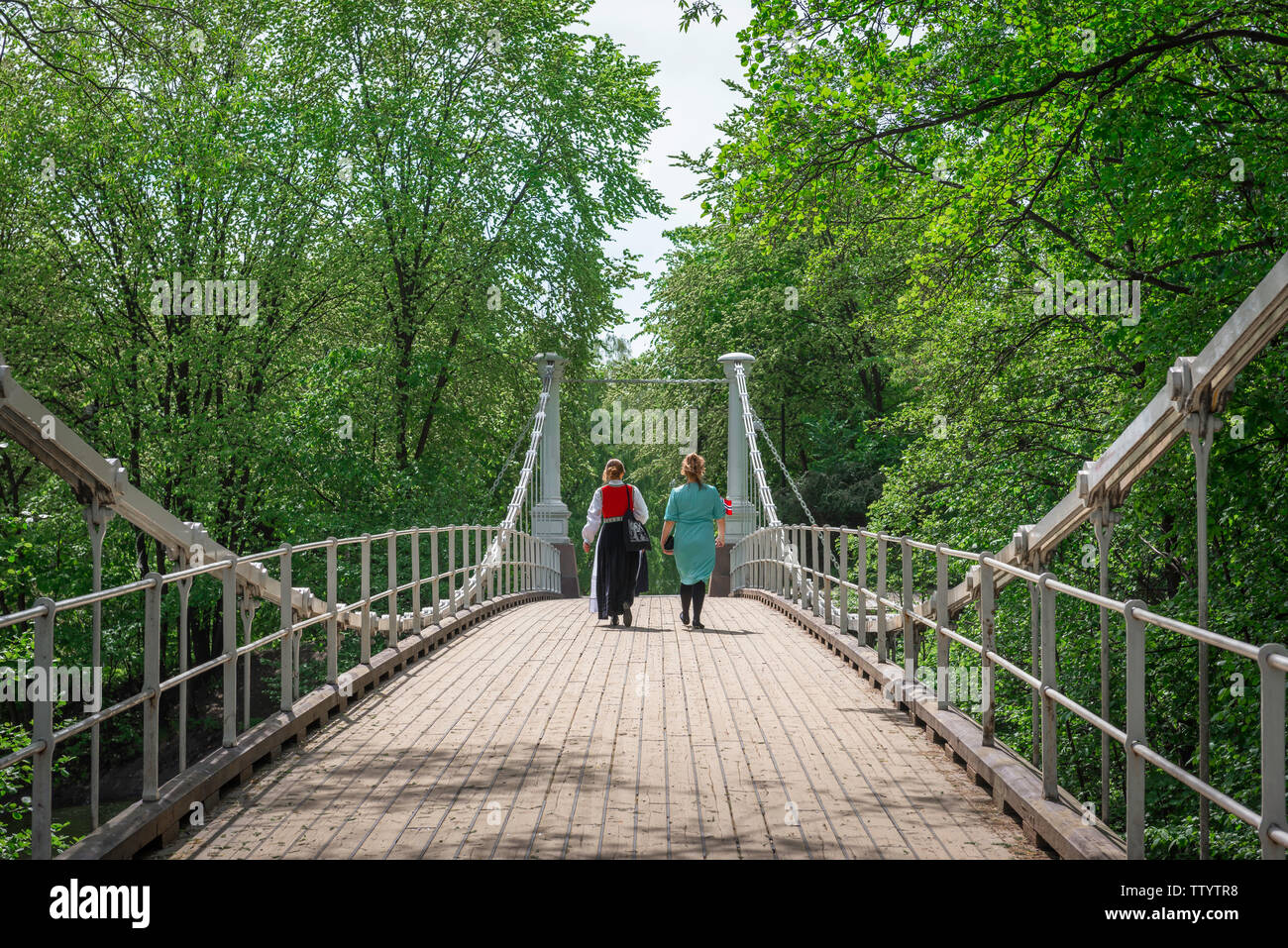 Ponte donna, vista posteriore di due donne norvegesi che attraversano il ponte Aamodt Bru sopra il fiume Akerselva nel distretto Grunerlokka di Oslo, Norvegia. Foto Stock