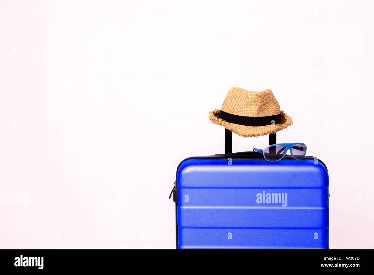 Occhiali da sole blu e paglia estate hat sul bagaglio blu isolate su sfondo bianco - con spazio di copia Foto Stock