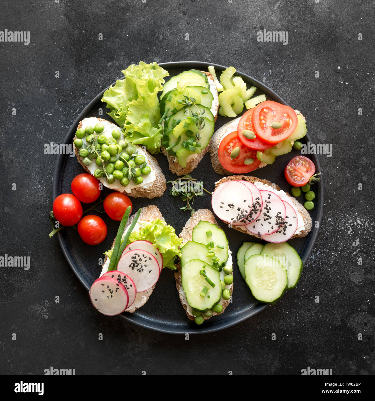 Vegano diversi panini con verdure, Rafano, sedano, pomodoro, pane di segale su sfondo nero. Top vew. Antipasto di partito. Lay piatto. Foto Stock