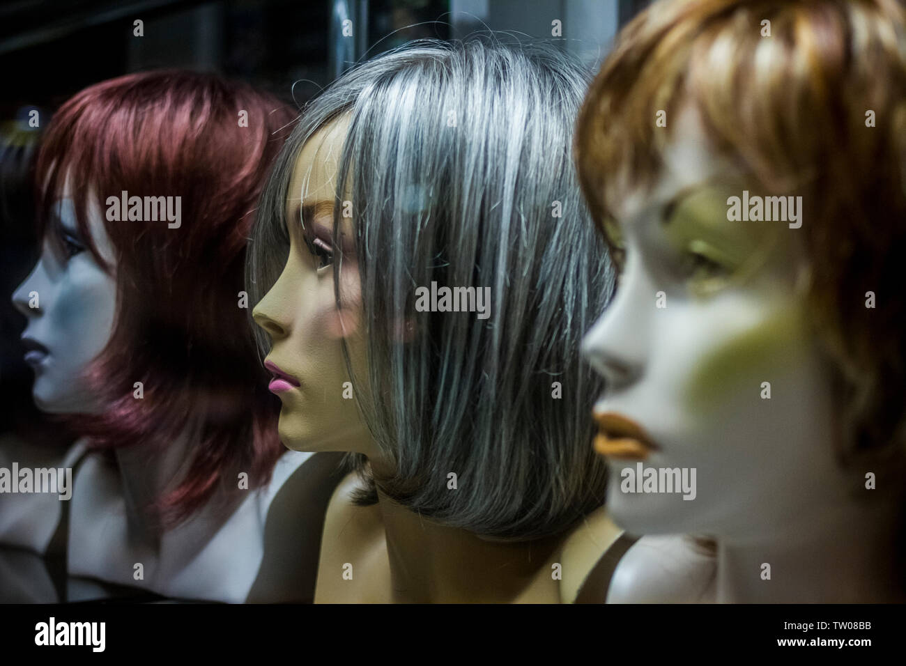 Parrucche visualizzato sul manichino teste in una vetrina di notte a Poznan, Polonia Foto Stock