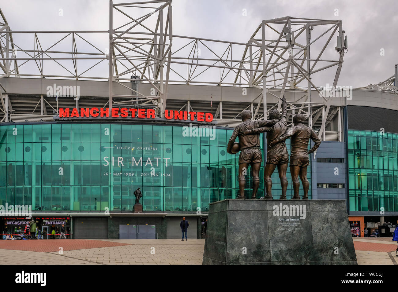 Old Trafford, Manchester, Regno Unito - 20 Gennaio 2019: vista posteriore iconica statua del migliore, diritto e Charlton con il Manchester United football Stadium di Foto Stock