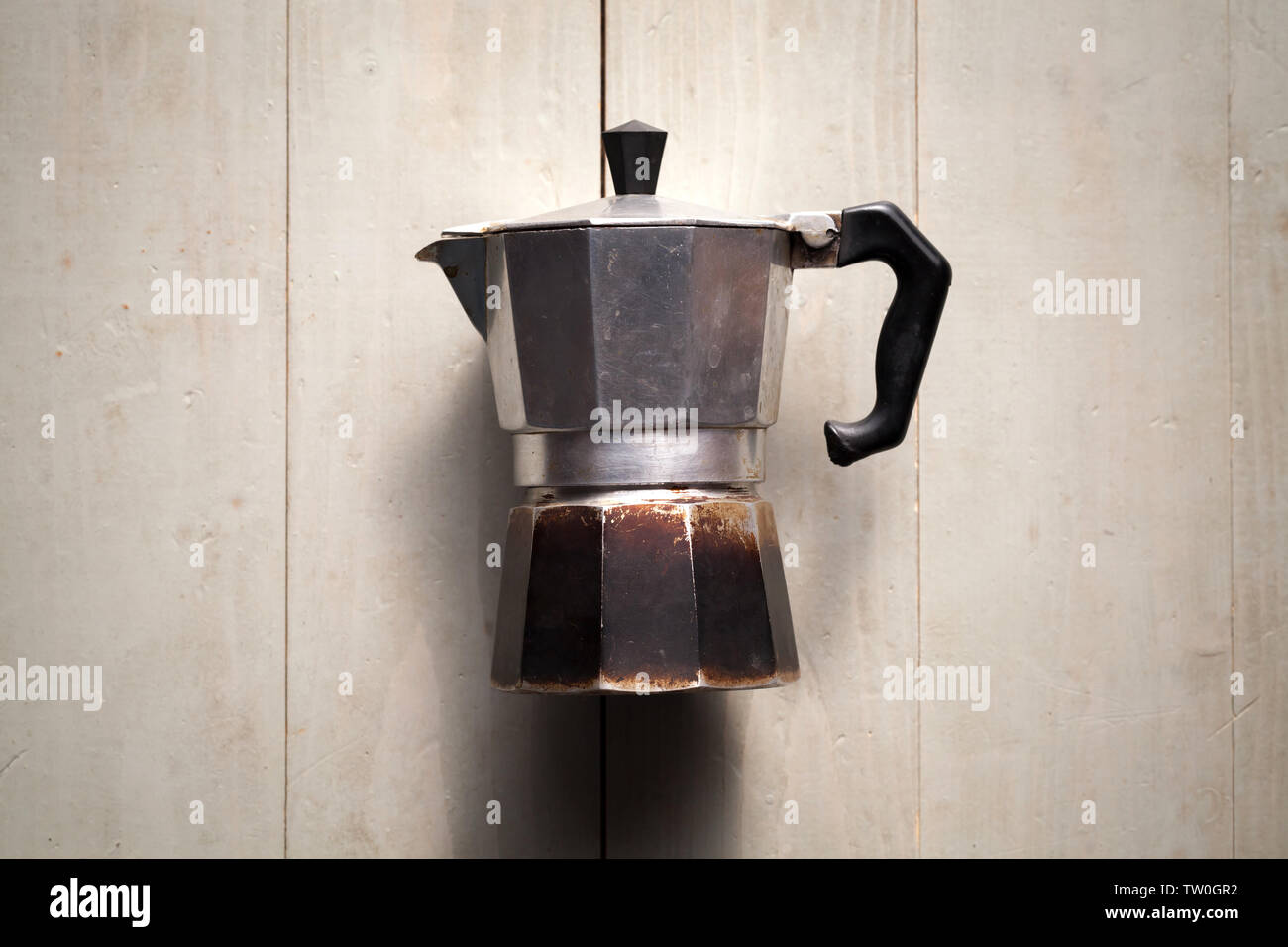 Vintage moka italiana pot laici bianco su un tavolo di legno. Si tratta di un vecchio fornello e macchina per il caffè che prepara il caffè facendo passare acqua bollente pressurizzata dal vapore Foto Stock