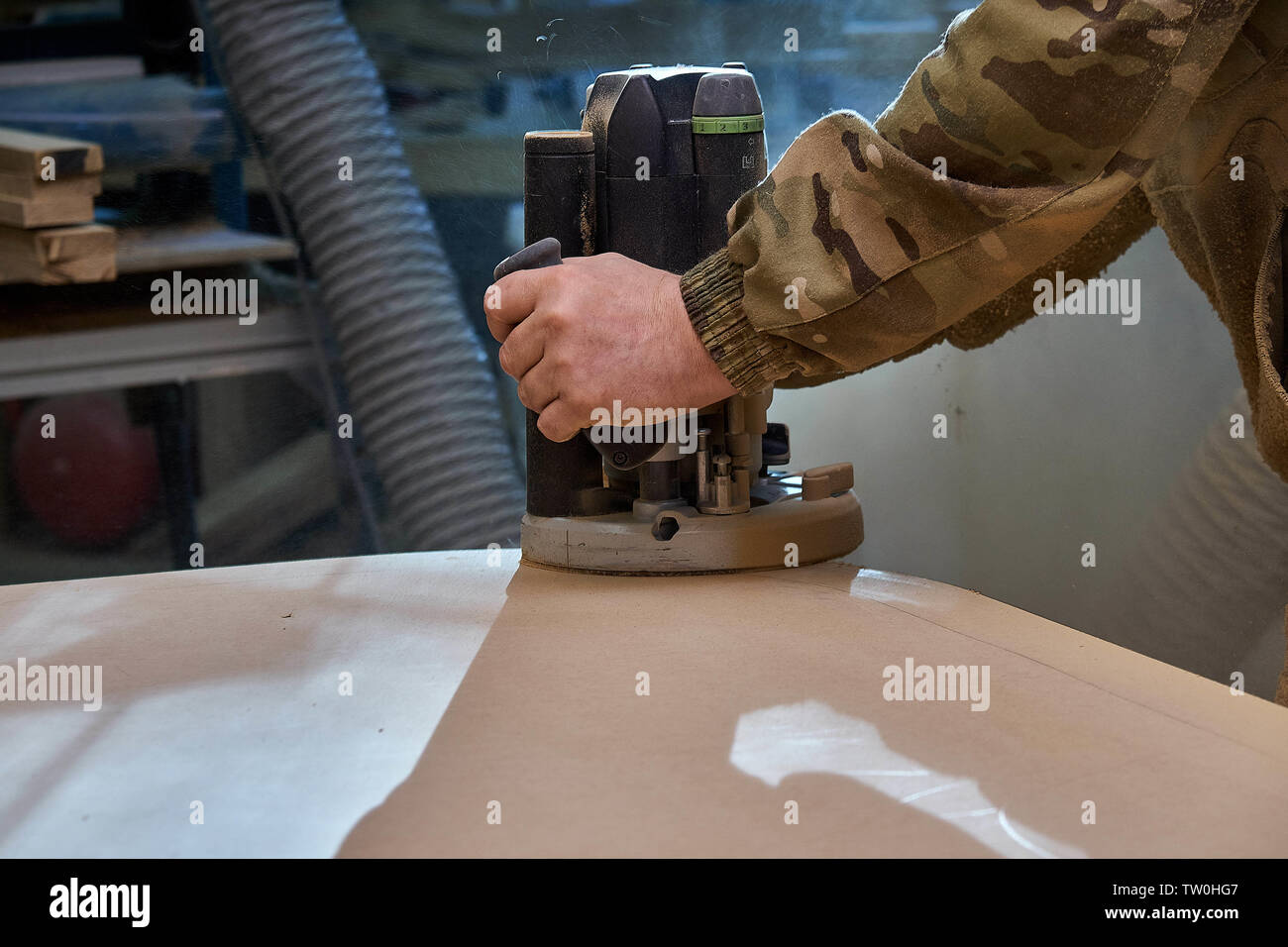 Carpenter lavora con mano manuale macchina fresatrice in officina. La fabbricazione di MDF tavolo. I mobili in legno del processo di fabbricazione Foto Stock
