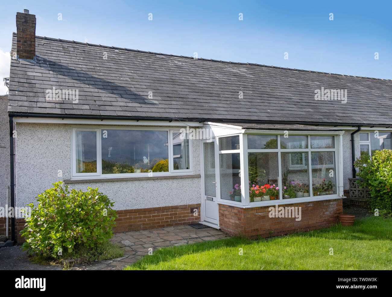 UK 60's bungalow con tetto in ardesia, quarzo bianco rendono upvc e finestre con doppi vetri e portico anteriore. Foto Stock