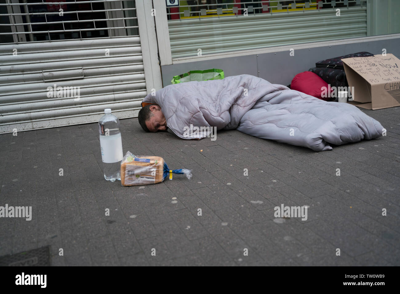 Uomo senza tetto con pane e acqua Foto Stock