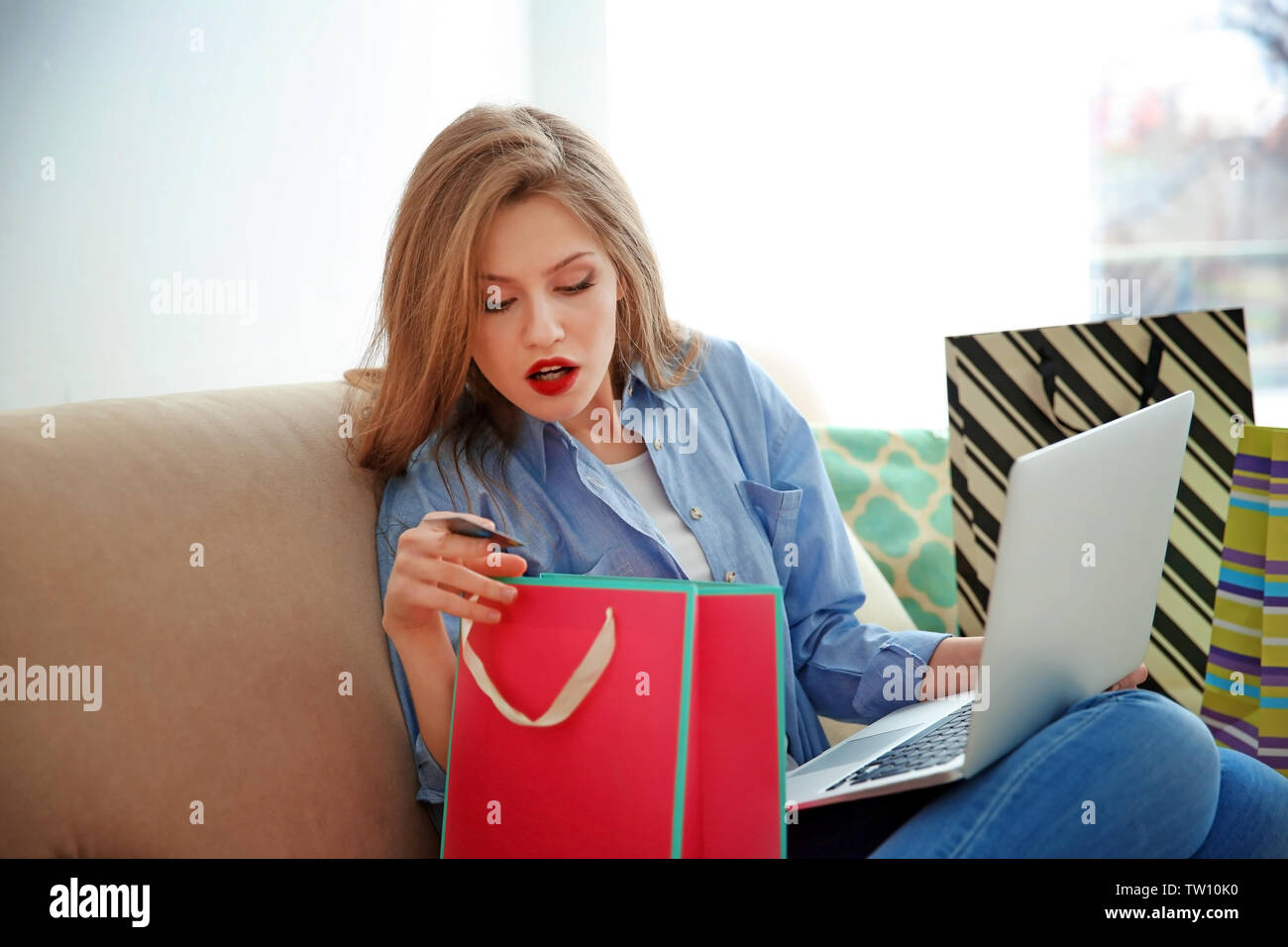 Bella giovane donna facendo shopping online a casa Foto Stock