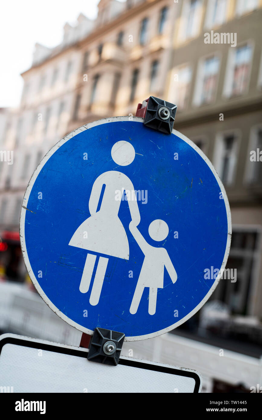 Primo piano di una zona pedonale segno di traffico in Germania, che raffigura la silhouette di un adulto tiene per mano un bambino in bianco su uno sfondo blu Foto Stock