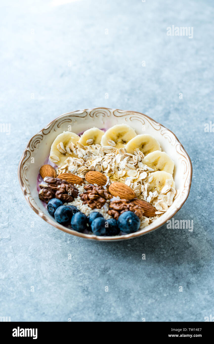 Acai ciotola con yogurt, Blackberry, fette di banana, noce, miele, marmellata, avena, mandorla, i semi di sesamo e granola in porcellana ciotola. Alimenti biologici. Foto Stock