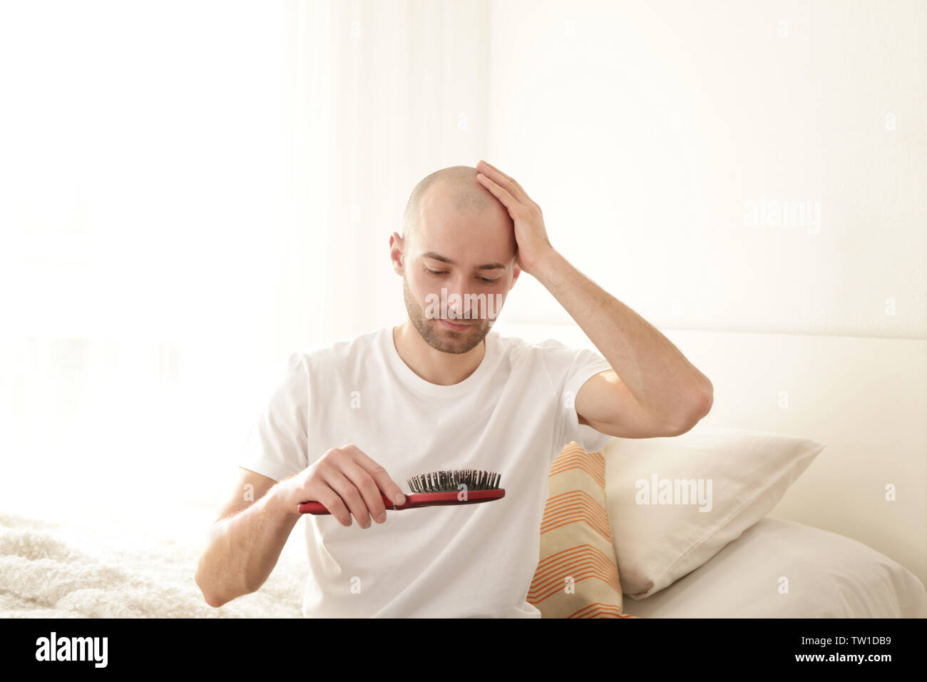 La perdita di capelli concetto. Giovane uomo con pettine a casa Foto Stock