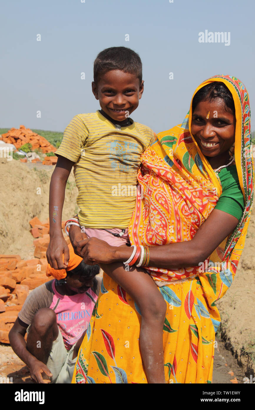 Donna che porta suo figlio in un cantiere, India Foto Stock