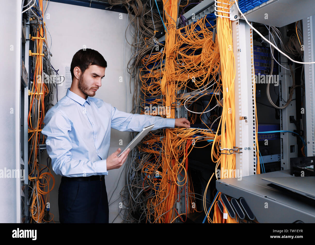 Bel giovane ingegnere con tablet pc lavorando in sala server Foto Stock