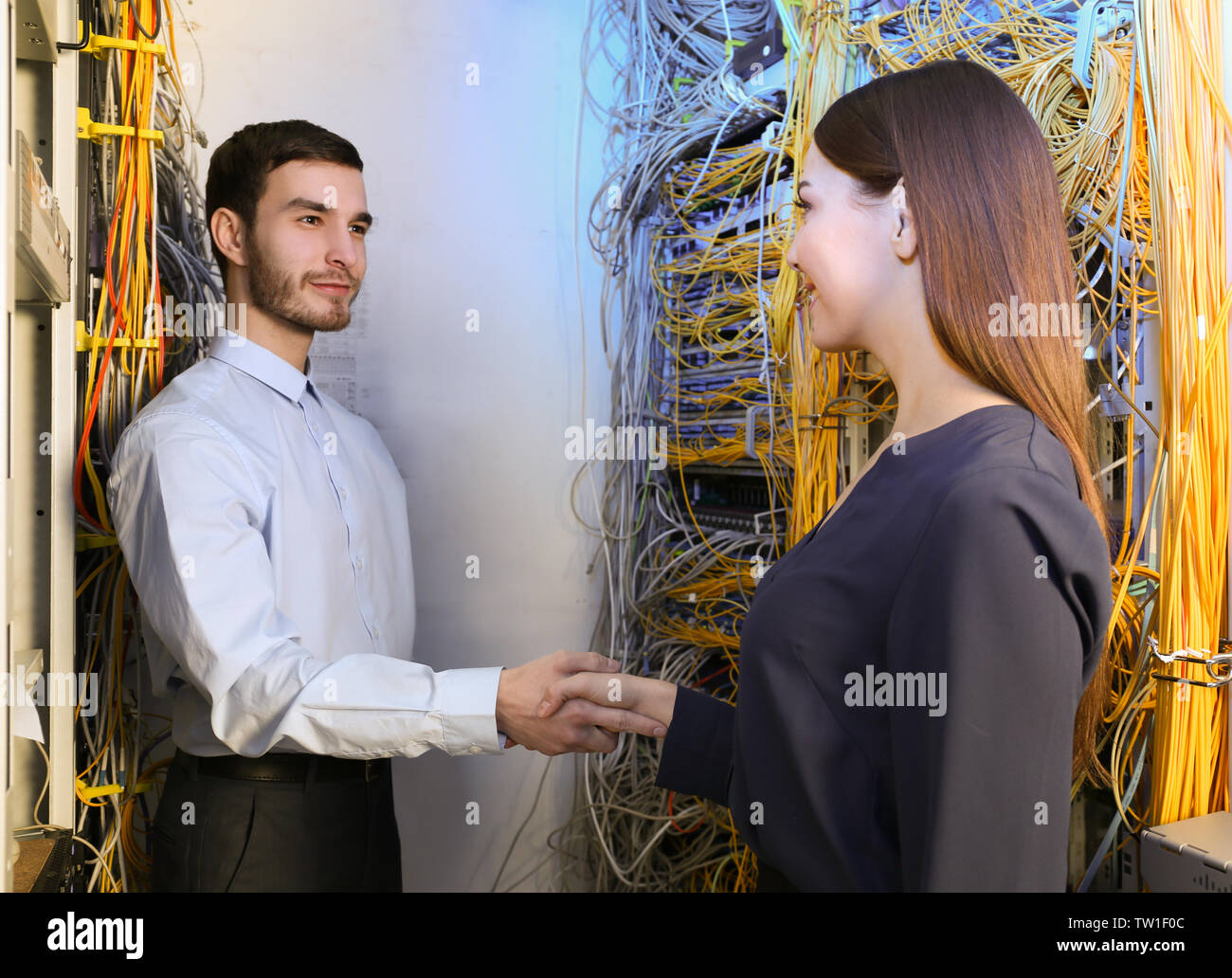 Giovani ingegneri si stringono la mano in sala server Foto Stock