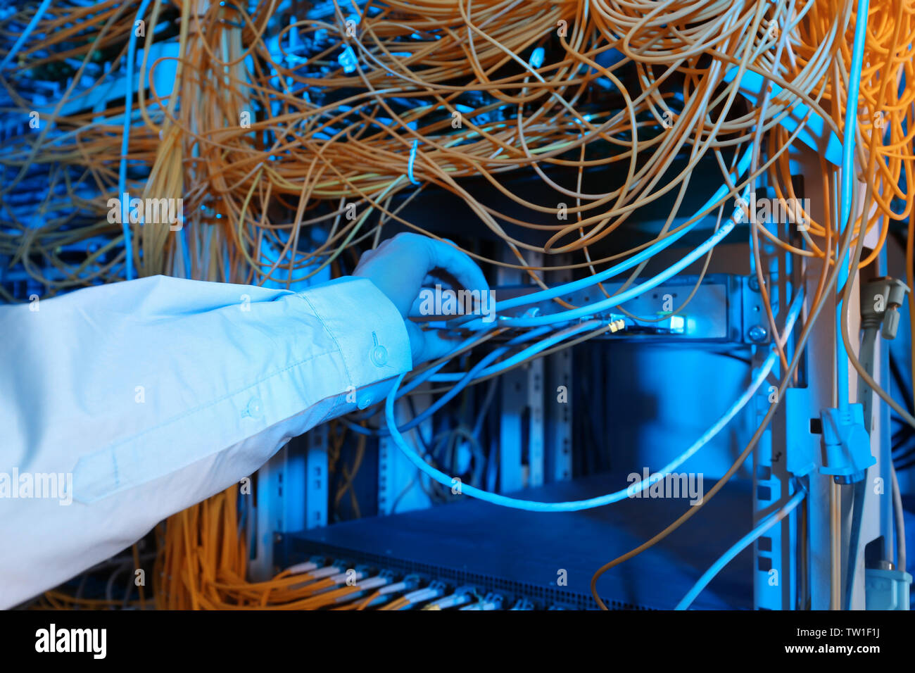 La mano del giovane ingegnere di cavi di collegamento in sala server Foto Stock
