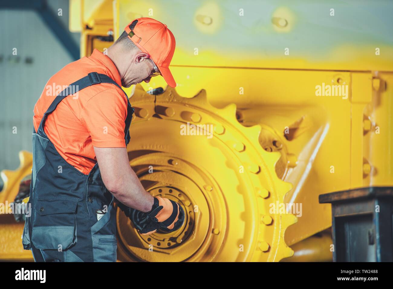 Per impieghi pesanti Bulldozer operazione di ricostruzione. Caucasian meccanico nel suo 30s Controllo sulla ruota di Caterpillar. Foto Stock