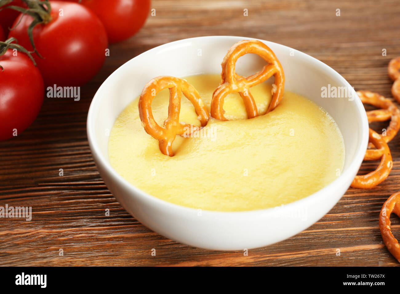 Immersione pretzel nella ciotola con salsa al formaggio sul tavolo da pranzo Foto Stock