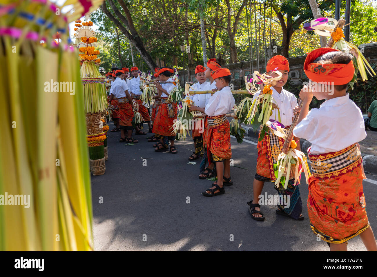 DENPASAR/BALI-Giugno 15 2019: Giovane ragazzo Balinese che indossano il tradizionale design Balinese copricapo e sarong tradizionale portare sampian alla cerimonia di apertura Foto Stock