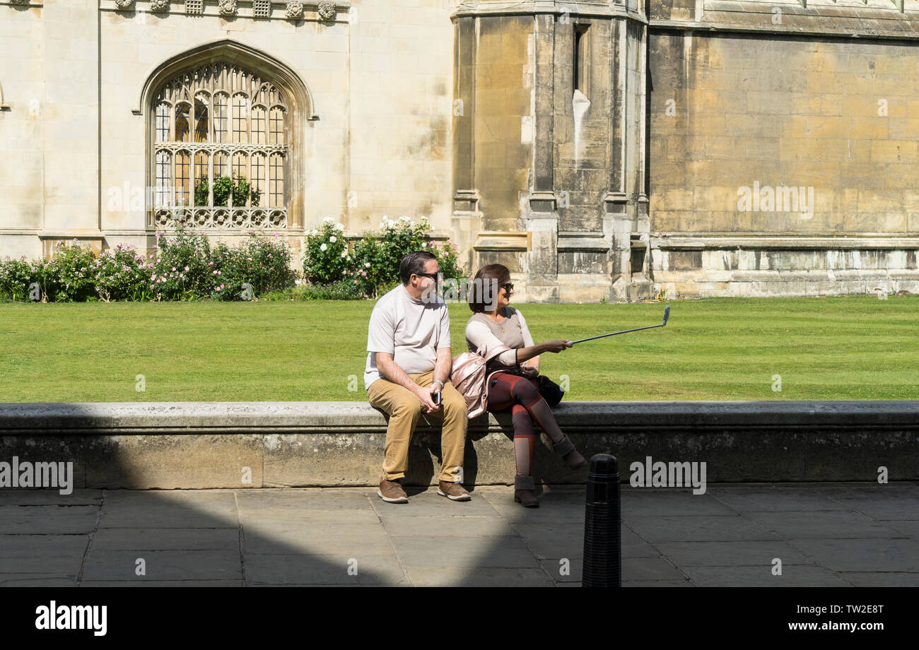 Giovane seduto sulla parete tenendo selfie nella parte anteriore del Kings College di Cambridge 2019 Foto Stock
