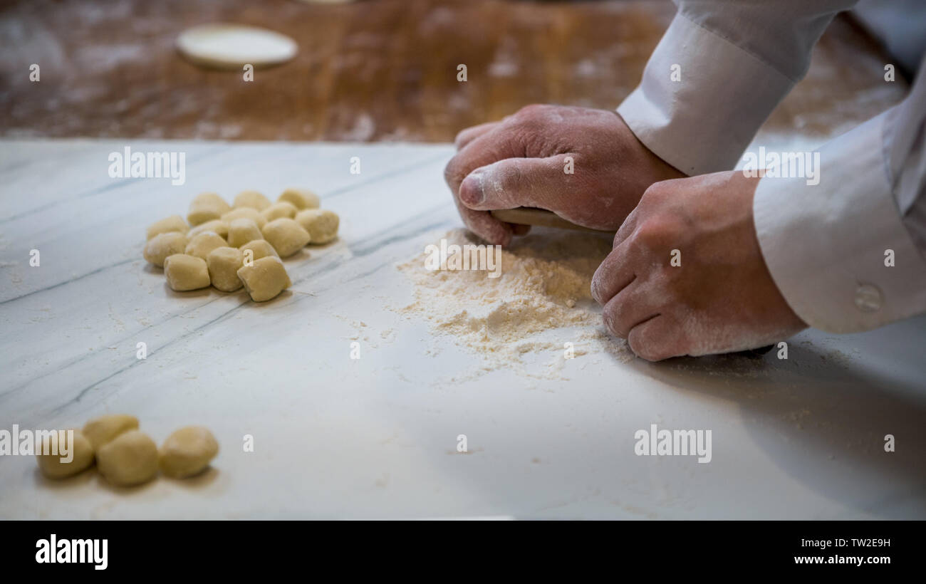 Un chef taiwanese rotola fuori pasta prima del suo riempimento con carne di creare jiaozi, un cinese gnocco. Uomo asiatico rendendo gnocchi di fresco in una cucina Foto Stock