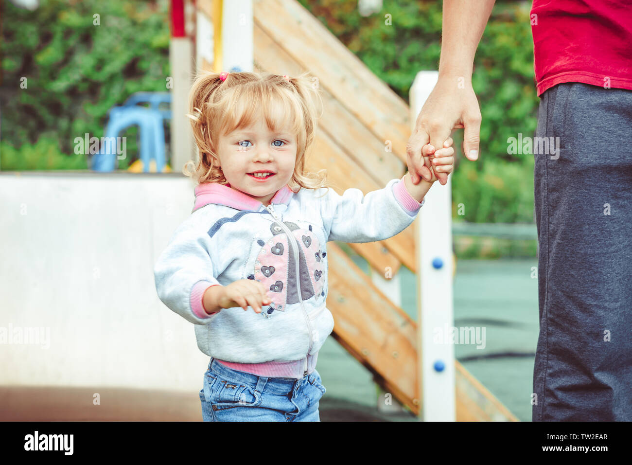 Il padre mantiene la mano della figlia di stand nel Parco Foto Stock