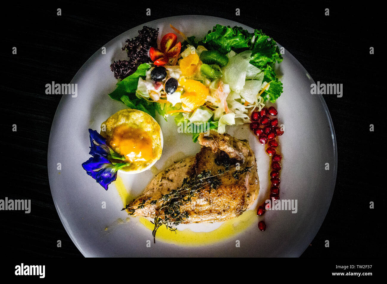 Il francese suprema di pollo pollo arrosto con patate gratinate e salsa di frutta e i semi di melograno e butterfly pea leaf Foto Stock