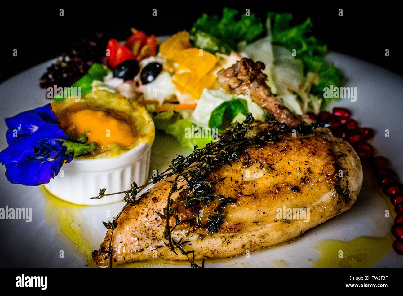 Il francese suprema di pollo pollo arrosto con patate gratinate e salsa di frutta e i semi di melograno e butterfly pea leaf Foto Stock