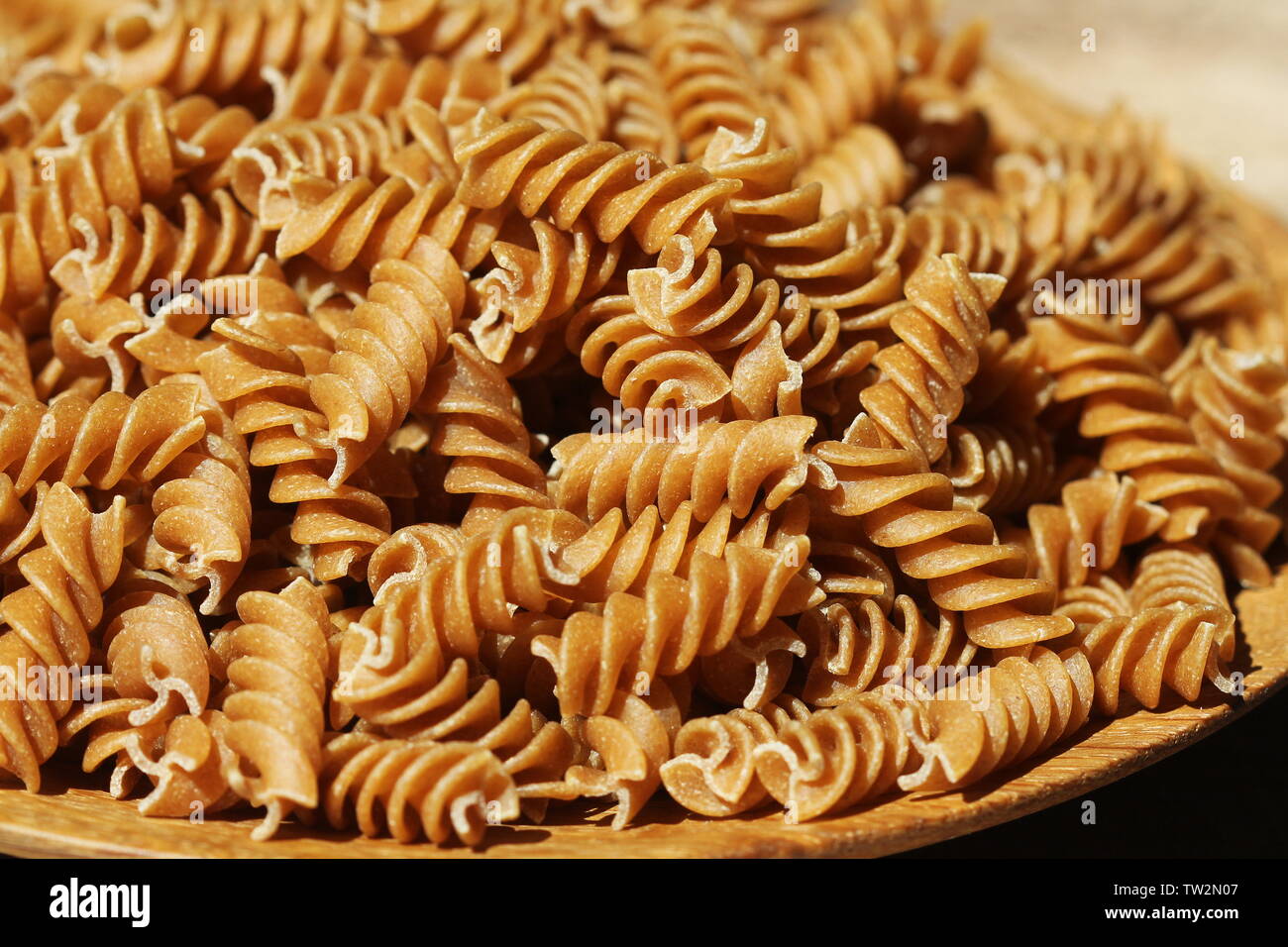 Fusilli integrali in un piatto. Pasta integrale su una tavola di legno . Foto Stock