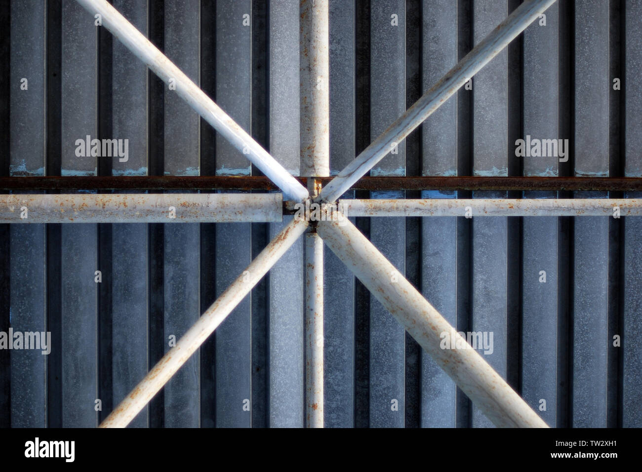 La struttura di supporto dei tubi in metallo zincato sotto il tetto del carport garage, abstract background industriale, otto raggi radiali di figura Foto Stock