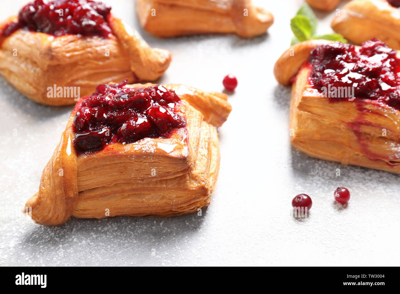 Una deliziosa pasticceria con confettura di ciliegie su sfondo chiaro Foto Stock