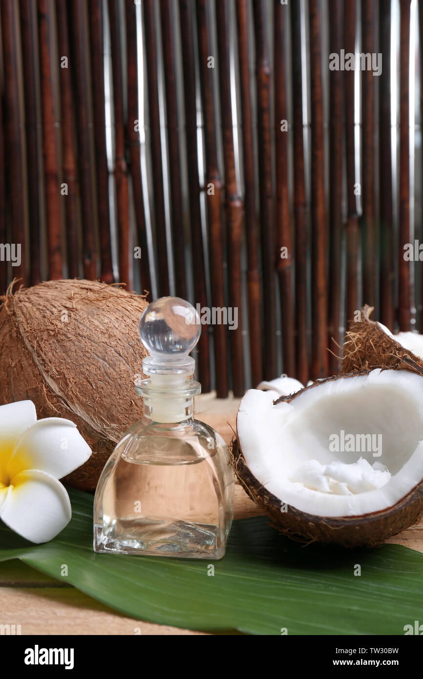 Composizione con olio di noce di cocco in bottiglia per il trattamento termale in foglia di palma Foto Stock