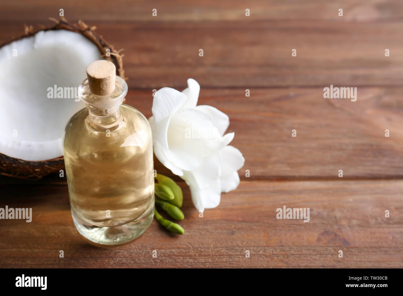 Composizione con olio di noce di cocco in bottiglia per il trattamento termale su sfondo di legno Foto Stock