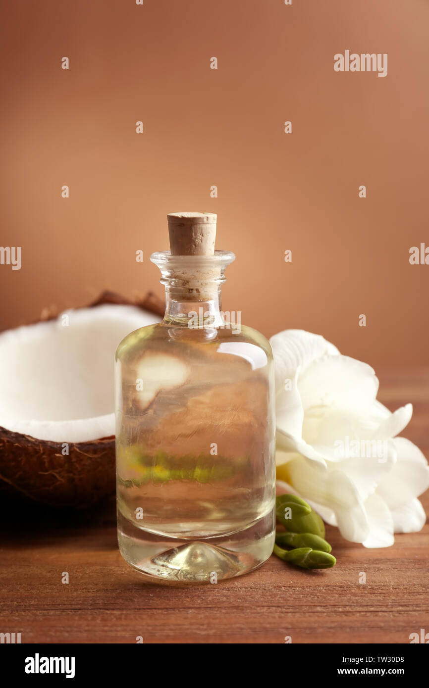 Composizione con olio di noce di cocco in bottiglia per il trattamento termale sul tavolo di legno Foto Stock