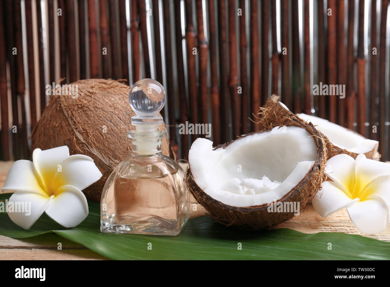 Composizione con olio di noce di cocco in bottiglia per il trattamento termale in foglia di palma Foto Stock