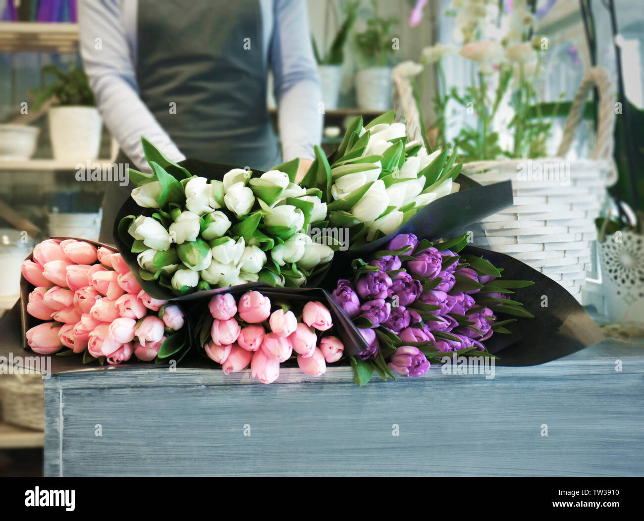 Fiorista femmina in piedi vicino al bancone con bellissimi mazzi di fiori in negozio di fiori Foto Stock