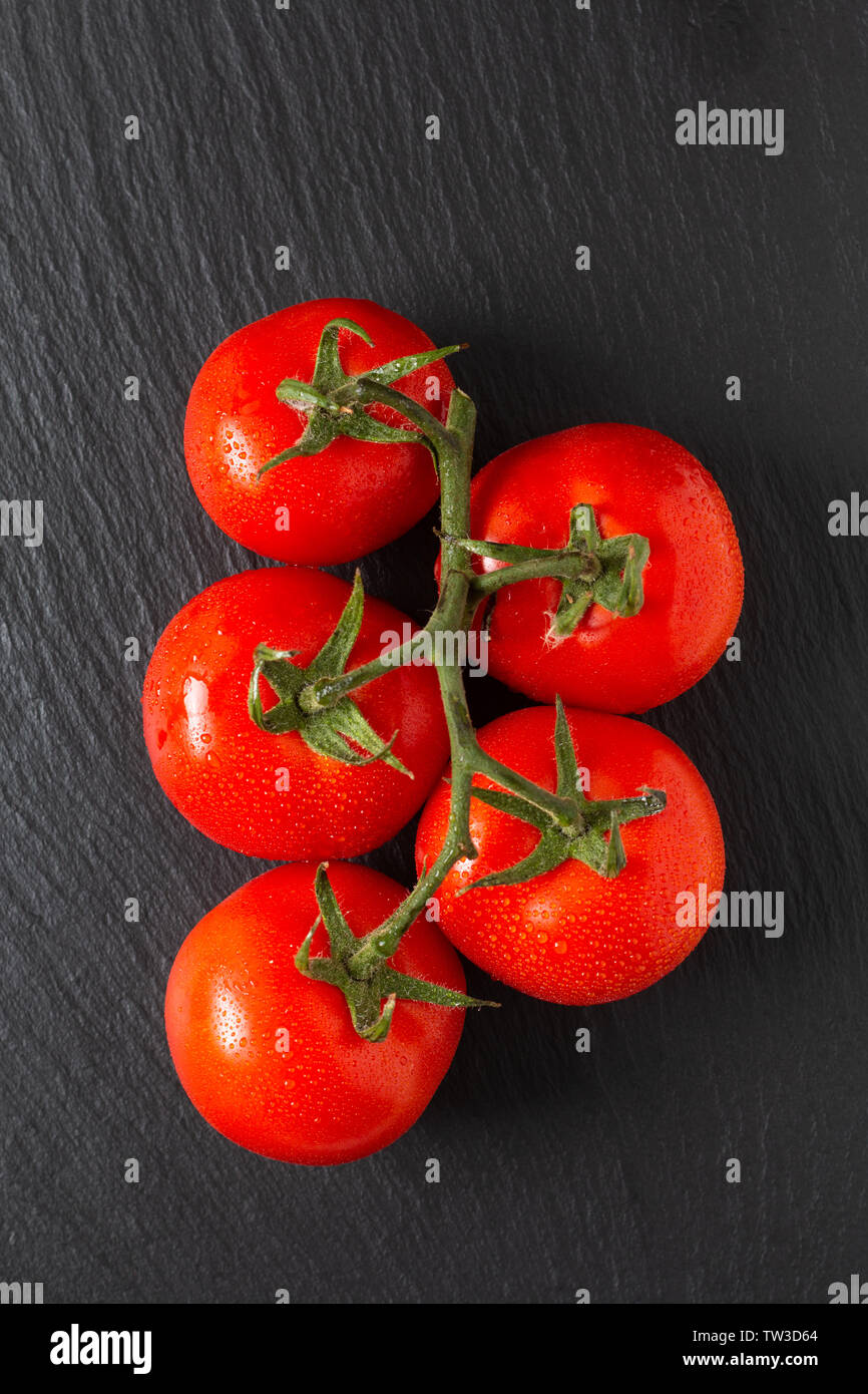 Concetto di cibo organico di pomodori in ardesia nera con scheda spazio di copia Foto Stock