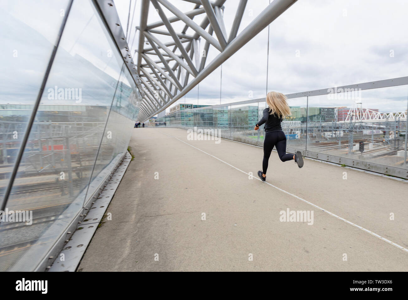Donna guida durante la rapida esecuzione di esercizio nella città moderna al giorno nuvoloso. Foto Stock