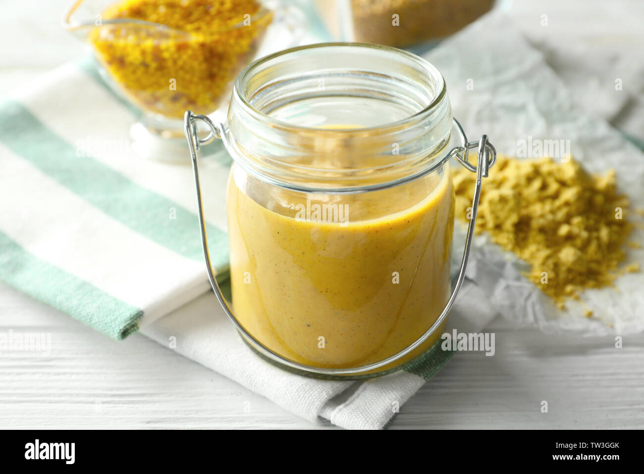 Vaso di vetro con una deliziosa salsa mostarda sul tavolo Foto Stock
