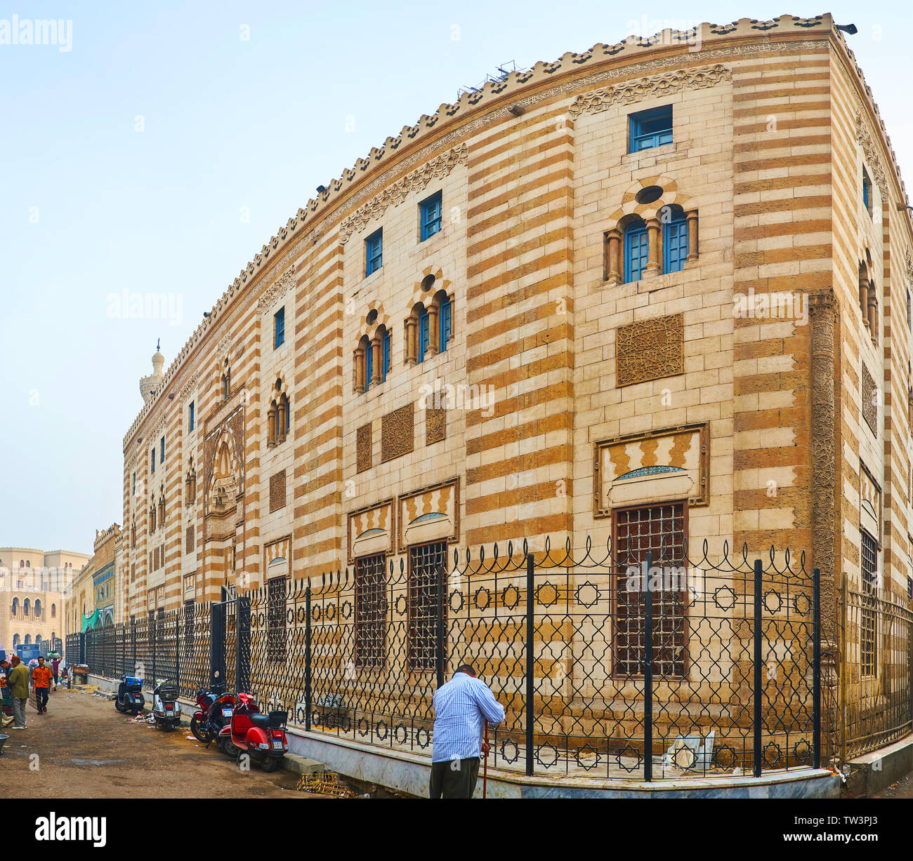 Il Cairo, Egitto - 22 dicembre 2017: la stretta strada malandato lungo la scenic scolpita in pietra della parete Al-Azhar moschea, decorate in Ablaq sty architettonico Foto Stock