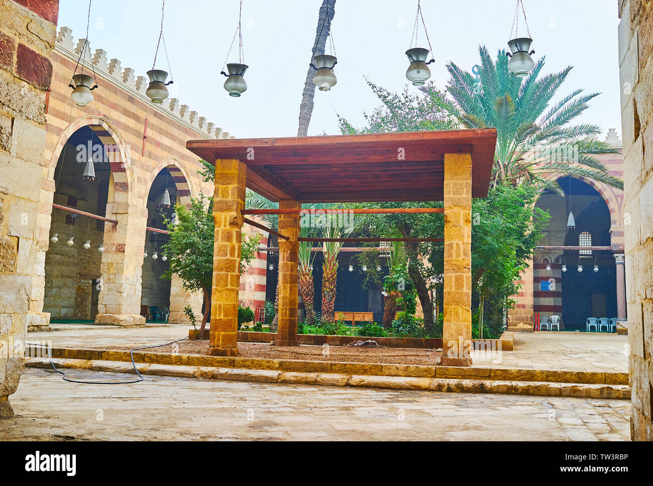 Il Cairo, Egitto - 22 dicembre 2017: il cortile di Aqsunqur (blu) Moschea con piccolo giardino di palme, arcade intorno ad esso e pergola in pietra sul primo piano, Foto Stock